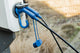 Blue Voldt Type 2 EV charging cable connector hanging on a charging station cable hook at sunset