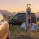 Camper van and car charging at a rural campsite power post at golden hour