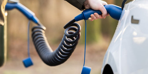 Coiled Type 2 charging cable held next to a white electric car to illustrate charging speed